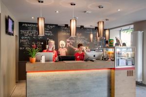 a restaurant with two people sitting at a counter at MEININGER Hotel Berlin Mitte in Berlin