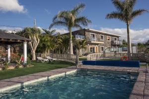 a swimming pool in front of a house with palm trees at San Diego in La Matanza de Acentejo