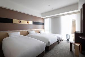 a hotel room with two beds and a window at Cross Hotel Kyoto in Kyoto