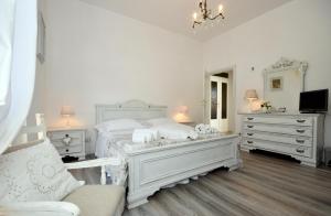 a white bedroom with a bed and two dressers at Shabby House Nonna Peppa in Campello sul Clitunno
