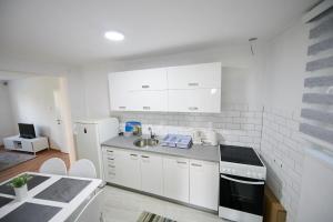 a white kitchen with a sink and a refrigerator at Lovely House Apartment in Sarajevo
