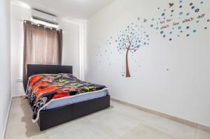a bedroom with a bed with a tree on the wall at Joy Apartments Gzira in Il-Gżira