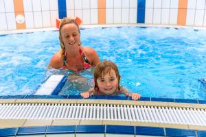 a woman and a child in a swimming pool at Camping Ginsterveld in Burgh Haamstede