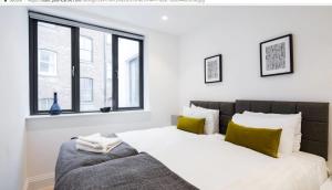 a white bedroom with a large bed with green pillows at Oxford Circus Apartments in London