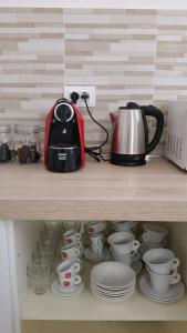 a shelf with a tea kettle and cups and plates at A Casa di Asia in Grosseto