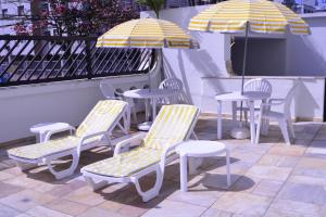 een groep stoelen en tafels met parasols op een patio bij Ap Enseada Lado Praia Ar Cond Piscina Wi-Fi 500Mb in Guarujá