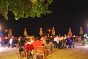 a large group of people sitting at a table with umbrellas at Tartaruga Hotel in Unawatuna