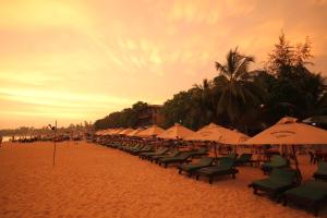 a beach area with chairs, tables and umbrellas at Tartaruga Hotel in Unawatuna