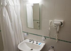 y baño con lavabo, espejo y ducha. en Hotel Milton en La Paz