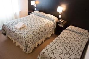 a hotel room with two beds and two tables at Hotel Milton in La Paz