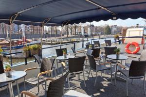 a patio with tables and chairs next to a river at Hotelboat Fleur in Amsterdam