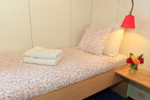 a bedroom with a bed with a lamp and a vase of flowers at Hotelboat Fleur in Amsterdam