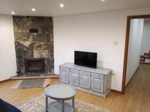 a living room with a tv and a fireplace at Casa de Paulus - Gerês in Geres