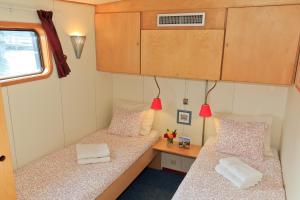 two beds in a small room with a desk at Hotelboat Fleur in Amsterdam