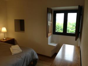 a room with a bed and a window and a table at Casa de Paulus - Gerês in Geres