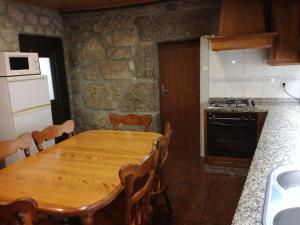 a kitchen with a wooden table and a stove top oven at Casa de Paulus - Gerês in Geres