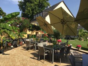 a patio with tables and chairs and umbrellas at Bed and Breakfast - Rheingauer Hof in Oestrich-Winkel