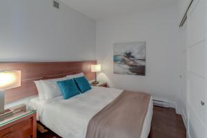 een slaapkamer met een groot bed met blauwe kussens bij Les Immeubles Charlevoix - Le 760504 in Québec