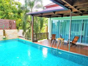 a swimming pool with a table and chairs next to a house at Prima Villas Karon Beach by PHR in Karon Beach