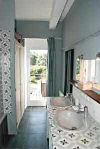 La salle de bains est pourvue de 2 lavabos et d'une grande fenêtre. dans l'établissement Gite de Mougeres, à Caux