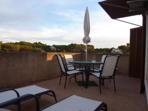 a patio with a table and chairs and an umbrella at Apartamentos Villa Primera in Cala Figuera