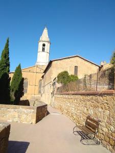 a bench sitting in front of a building with a tower at L'apparita Camere in Pienza