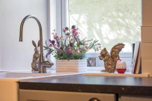 eine Küchentheke mit einem Waschbecken mit Blumen und einem Fenster in der Unterkunft Country Nest in Carnwath
