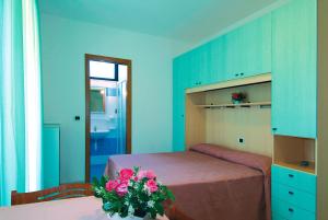ein Schlafzimmer mit einem Bett und einem Tisch mit einer Blumenvase in der Unterkunft Hotel Residence Margherita in Tortoreto Lido