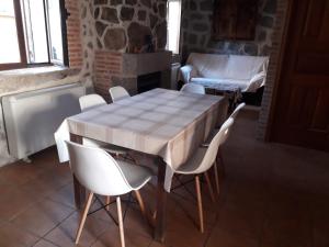 a dining room with a table and white chairs at Casa Luz in Ávila