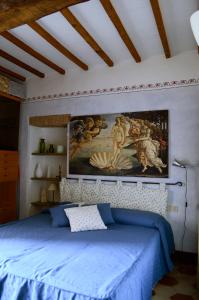 a bedroom with a blue bed with a painting on the wall at Casa di Luli in Siena