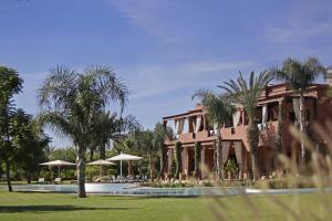 a building with palm trees and a swimming pool at Villa Grace in Marrakesh