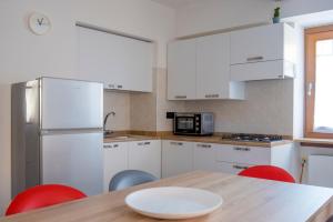 a kitchen with white cabinets and a wooden table with red chairs at B21 in Arco