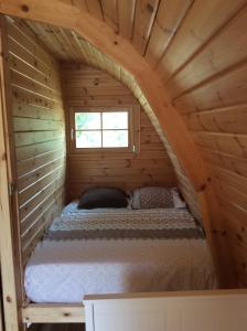 a bed in a log cabin with a window at POD des deux chênes in Louroux-Hodement
