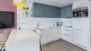a white kitchen with blue cabinets and a tv at The Hype Beachhouse in Playa de Palma
