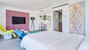 a bedroom with a large white bed and a yellow chair at The Hype Beachhouse in Playa de Palma