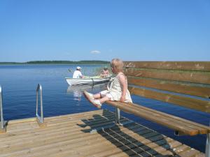 a young girl sitting on a bench at a dock at B&B Lomamokkila in Savonlinna