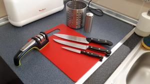 a red cutting board with knives on top of a counter at Amazing terrace in Águilas in Águilas