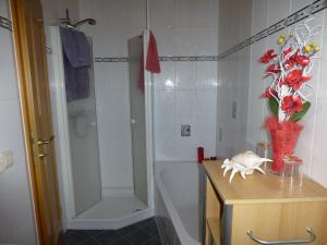 a bathroom with a tub and a shower with a vase of flowers at Studio Orchidee in Weißig