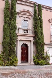 a building with a red door and two trees at Casa Toscana Bed & Breakfast in San Miguel de Allende