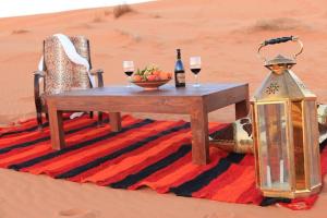 扎戈拉的住宿－Karim Sahara Prestige，沙漠中的一张桌子,放上两杯葡萄酒