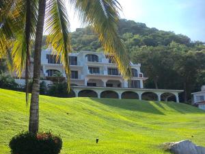 a large white building on a hill with palm trees at Palma Real in Manzanillo