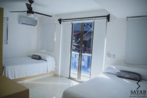 Cette chambre blanche dispose de deux lits et d'une fenêtre. dans l'établissement Hotel Sayab 5ta Avenida, à Playa del Carmen