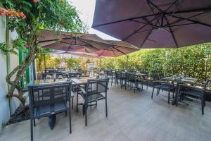 a patio with tables and chairs and umbrellas at Mandarina Hotel Luxembourg Airport in Luxembourg