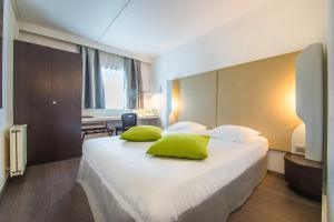 a bedroom with a large white bed with green pillows at Mandarina Hotel Luxembourg Airport in Luxembourg +30 photos