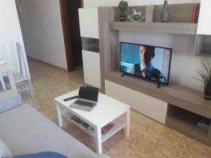 een woonkamer met een televisie en een laptop op een tafel bij Burrero Seasight in Ingenio