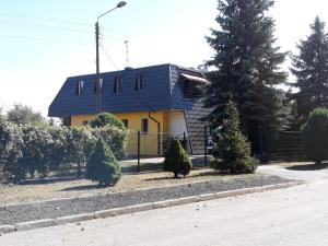 a house with a blue roof and some trees at Rooms noclegi in Bytyń