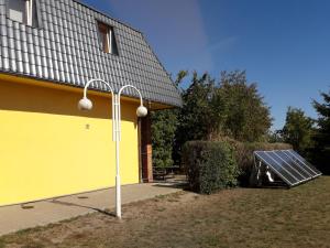 a solar panel next to a yellow building with a house at Rooms noclegi in Bytyń