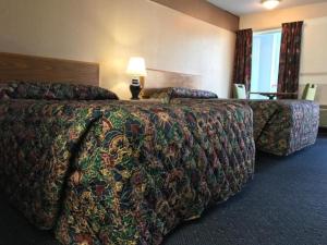 a hotel room with two beds and a table with a lamp at American Motel in Wheat Ridge