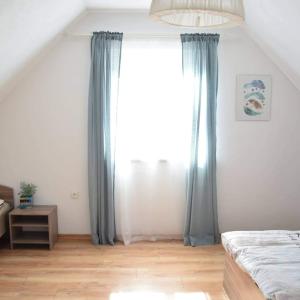 ZałakowoにあるStanlejówkaのベッドルーム(青いカーテン、大きな窓付)