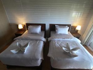 2 Betten mit weißer Bettwäsche und Blumen drauf in der Unterkunft BatuRundung Surf Resort in Naibos